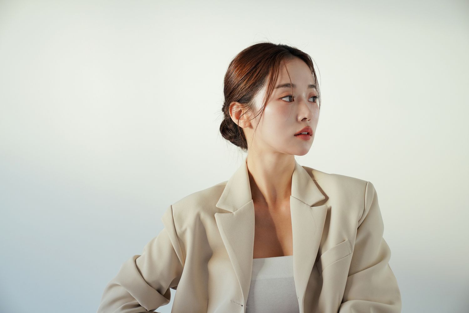 Woman in beige blazer looking to the side.
